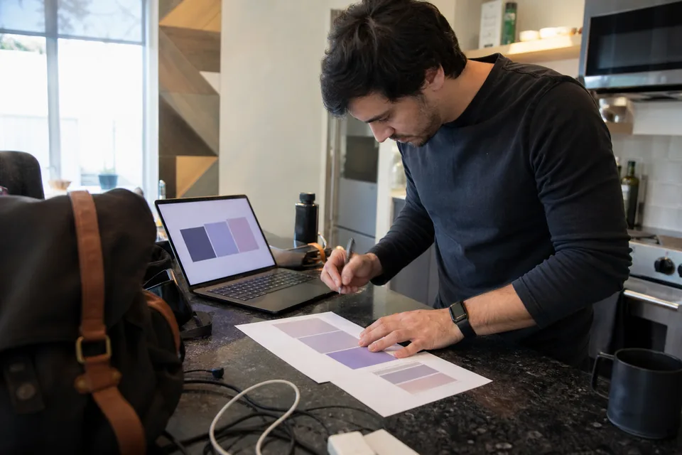 SaaS founder comparing subscription software quotes on paper next to a laptop