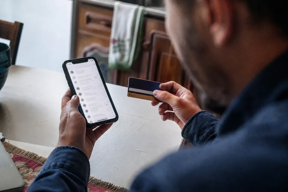 Hands holding a phone with an email open next to a payment card