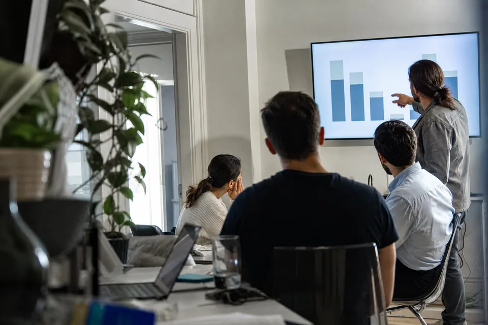 Founders in a meeting room reviewing churn benchmark charts on a screen