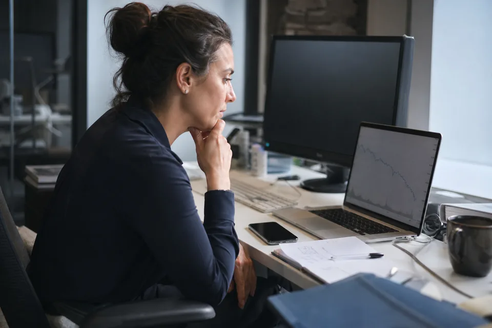 Finance lead at a desk reviewing a subscription revenue chart on a laptop