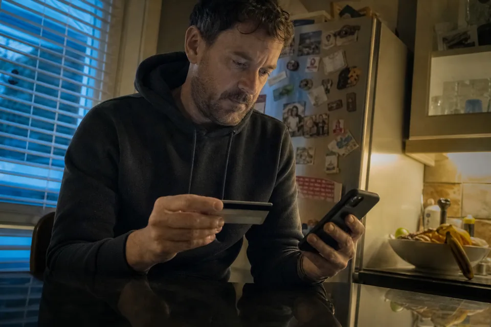 Subscriber holding a payment card and a phone while updating card details